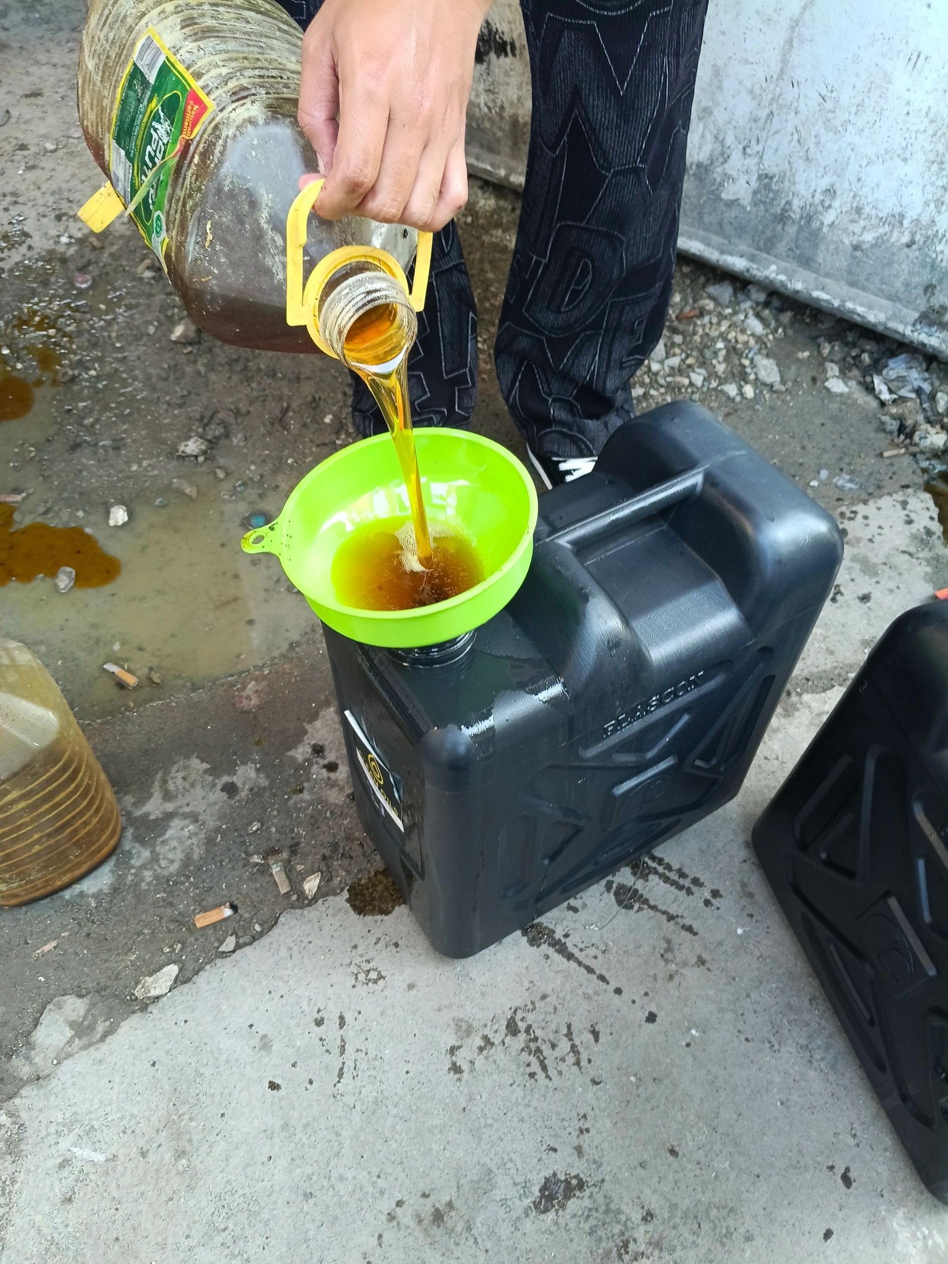Used cooking oil poured through a funnel into a sealed container